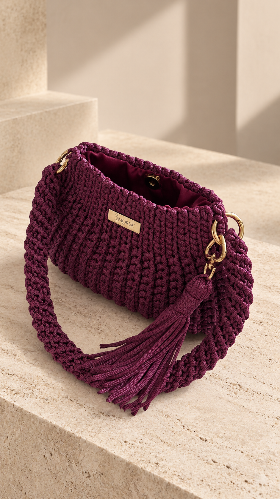 Burgundy crochet Jolie shoulder bag shown open, revealing the lined interior, on a stone step.